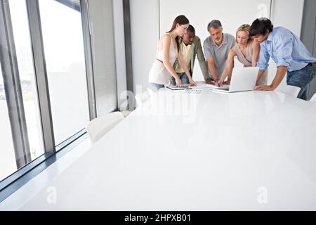 Axé sur l'avenir de leur entreprise. Un groupe de personnes en voyage d'affaires assis autour d'une table de réunion. Banque D'Images