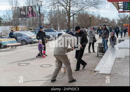 Le musicien de rue joue des instruments de musique devant le centre commercial. Homme mature avec un violon électronique. Les passants mettent de l'argent dans une boîte devant le Banque D'Images