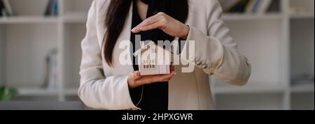 Maison couverte de mains de femme - assurance concept immobilier. Banque D'Images