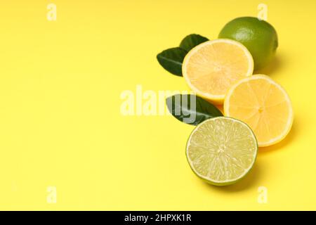 Demi-citron et citron vert avec feuilles sur fond jaune Banque D'Images