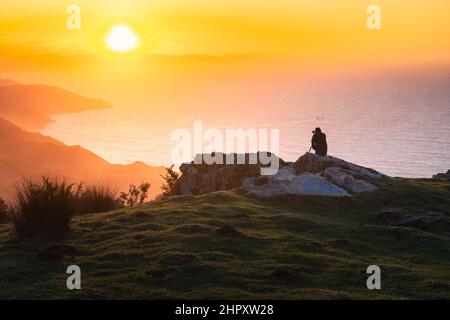 Photographe silhouette prendre des photos sur le sommet de la montagne de Jaizkibel au coucher du soleil. Banque D'Images