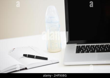 Il y a toujours quelque chose qui doit être fait Image rognée d'un ordinateur portable avec un journal ouvert à côté. Banque D'Images