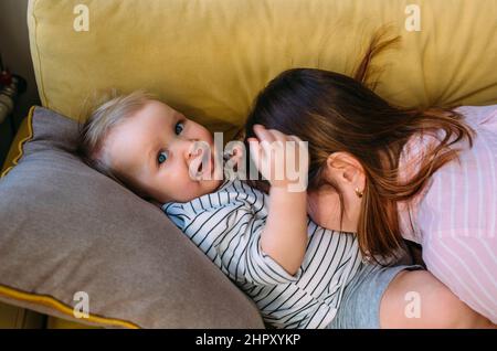 Maman joue à la maison avec un petit enfant sur le canapé, Amuse-toi bien. Banque D'Images