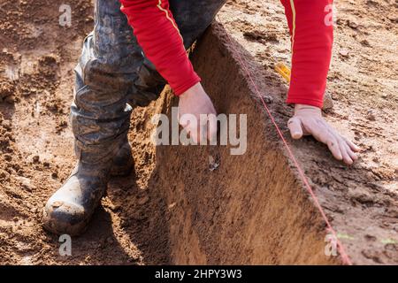 Breisach, Allemagne. 23rd févr. 2022. Un archéologue prépare un site d'excavation. Comme des traces de colonies romaines avaient déjà été découvertes à plusieurs reprises sur ce site en 1950s et 60s, des fouilles archéologiques de sauvetage étaient nécessaires pour documenter le patrimoine culturel. Les découvertes fournissent la preuve de l'activité active de peuplement dans la région, avec des traces datant de la période néolithique. Credit: Philipp von Ditfurth/dpa/Alay Live News Banque D'Images