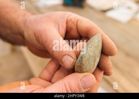 Breisach, Allemagne. 23rd févr. 2022. Un archéologue tient une lame de hache du néolithique (nouvel âge de pierre). Comme des traces de colonies romaines avaient déjà été découvertes à plusieurs reprises sur ce site en 1950s et 60s, des fouilles archéologiques de sauvetage étaient nécessaires pour documenter le patrimoine culturel. Les résultats fournissent la preuve de l'activité active de peuplement dans la région, avec des traces remontant à la période néolithique. Credit: Philipp von Ditfurth/dpa/Alay Live News Banque D'Images