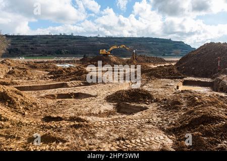 Breisach, Allemagne. 23rd févr. 2022. Une pelle hydraulique travaille sur la zone d'excavation tandis que les fosses déjà creusées sont visibles au premier plan. Comme des traces de colonies romaines avaient déjà été découvertes à plusieurs reprises sur ce site en 1950s et 60s, des fouilles archéologiques de sauvetage étaient nécessaires pour documenter le patrimoine culturel. Les découvertes fournissent la preuve de l'activité active de peuplement dans la région, avec des traces datant de la période néolithique. Credit: Philipp von Ditfurth/dpa/Alay Live News Banque D'Images