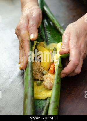 Femme indigène qui cuisine typiquement colombienne et mexicaine plat traditionnel appelé tamal Banque D'Images