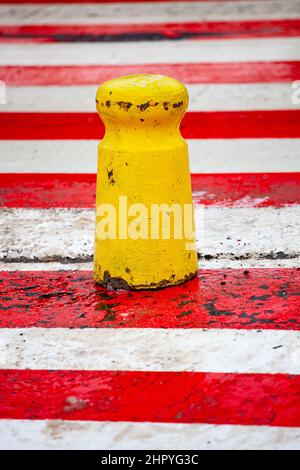 Poteau en béton jaune sur un tableau de bord rouge et blanc. Barrière de stationnement au passage à Zèbre. Banque D'Images