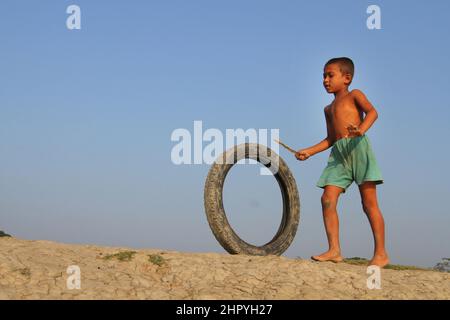 Khulna, Bangladesh - 08 octobre 2014 : un enfant joue avec un pneu de moto dans la zone côtière de Khulna, au Bangladesh. Banque D'Images