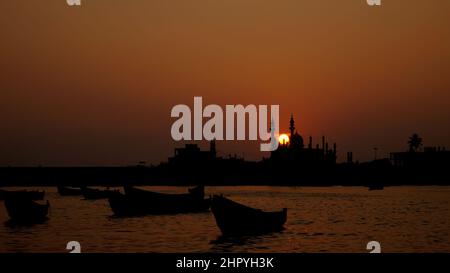 Belle vue silhouettée de petits bateaux dans l'eau et des bâtiments au coucher du soleil Banque D'Images