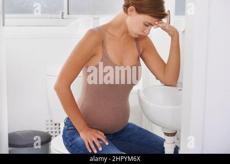 Des vagues de nausées. Une femme enceinte aux prises avec la maladie du matin dans la salle de bains. Banque D'Images