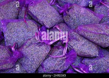 Plein cadre gros plan de fleurs de lavande parfumées nouées avec un ruban violet dans des sacs violets translucides. Tourné dans un marché français. Banque D'Images