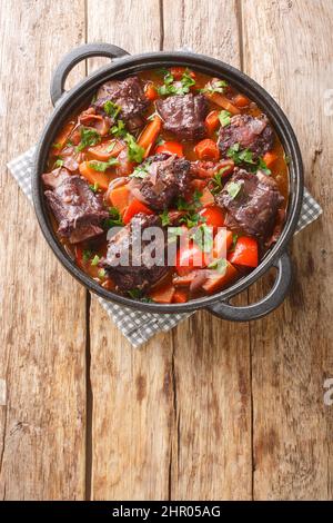 Stew Rabo de Toro espagnol à queue de taureau ferme sur une casserole sur la table en bois. Vue verticale du dessus Banque D'Images