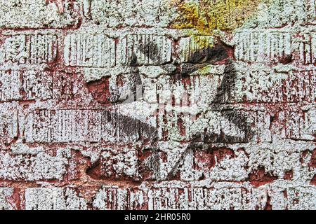 Mur de briques peint rugueux avec étoile encirée sur lui - arrière-plan Grunge. Banque D'Images