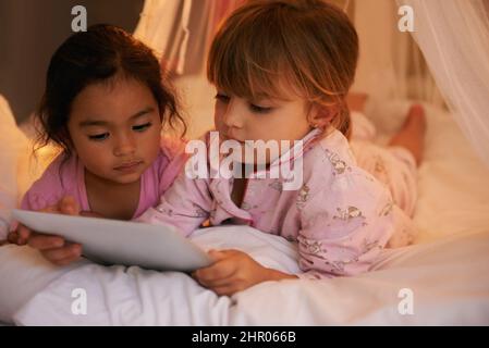 J'ADORE les lueurs. Photo de deux petites filles mignonnes lisant une histoire ensemble. Banque D'Images