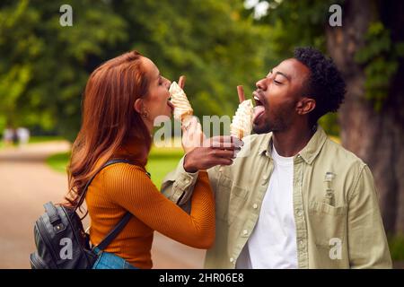 Jeune couple voyageant ensemble à travers la ville Eating Ice écres dans le parc Banque D'Images