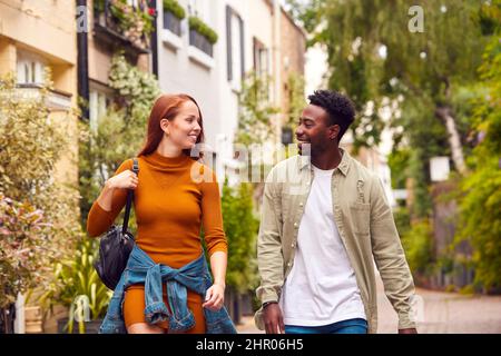 Jeune couple traversant la ville en marchant le long de la rue ensemble Banque D'Images