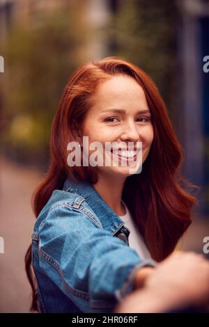 Point de vue prise de vue de la jeune femme dirigeant l'homme à travers la rue de ville par la main Banque D'Images