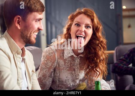 Femme en jeune couple faisant le visage assis sur canapé parlant ensemble pendant que les amis se rencontrent à la maison Banque D'Images