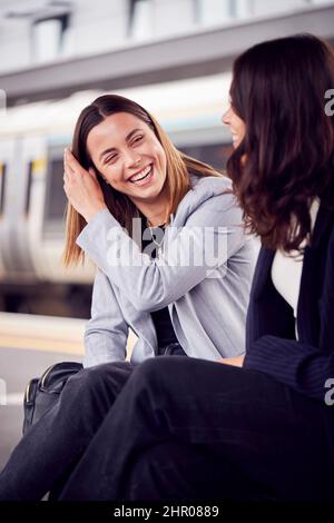 Deux femmes d'affaires qui se font du travail attendent le train sur la plate-forme de la gare pour discuter ensemble Banque D'Images