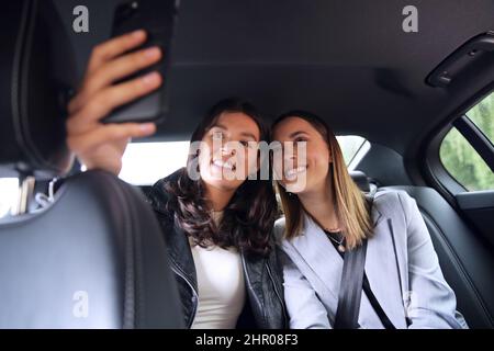 Femmes d'affaires qui se font des affaires pour travailler à l'arrière de la voiture ou de taxi prendre Selfie sur le téléphone mobile Banque D'Images