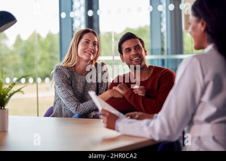 Femme médecin discutant des résultats des tests avec couple souriant n Hôpital Banque D'Images