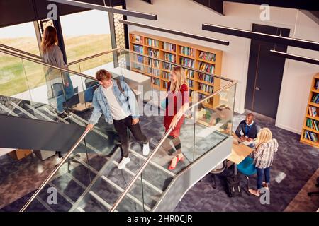 Les étudiants masculins et féminins dans l'Université ou le bâtiment de l'université très fréquentés parlent pendant qu'ils se rencontrent sur les escaliers Banque D'Images
