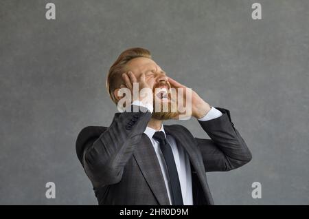 Un homme d'affaires caucasien fou et en colère hurle bruyamment et avec colère la tête. Banque D'Images