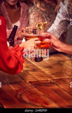 Gros plan sur des amis qui s'amusent la nuit à boire au bar pour faire un toast Banque D'Images