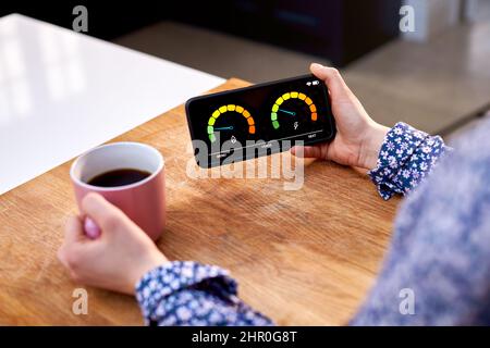 Gros plan d'une femme tenant un compteur d'énergie intelligent dans la cuisine mesure de l'électricité et de la consommation de gaz domestiques Banque D'Images