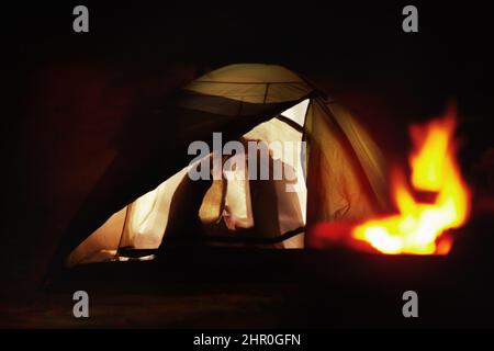 Des moments tendres en campant. Vue sur la silhouette d'un jeune couple embrassant dans une tente. Banque D'Images