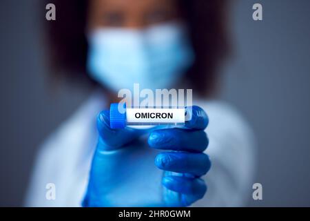 Femme travailleuse de recherche en laboratoire portant un manteau de laboratoire tenant un tube à essai étiqueté vaccin Banque D'Images