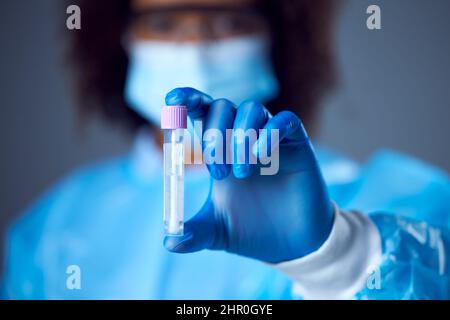 Femme de laboratoire en EPI avec lunettes de sécurité et test de maintien du masque facial pour le test PCR d'ADN à écoulement latéral Banque D'Images