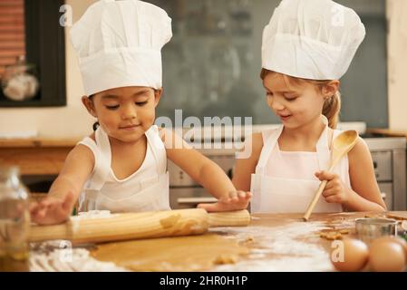 La pâtisserie est tellement amusante. Deux petites filles cuisant ensemble dans la cuisine. Banque D'Images