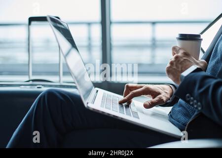 homme d'affaires avec un café à emporter à l'aide d'un ordinateur portable dans l'attente Banque D'Images