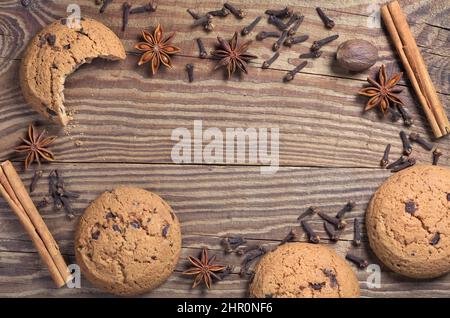 Fond en bois avec biscuits aux flocons d'avoine au chocolat et diverses épices d'hiver. Vue de dessus avec espace pour le texte au milieu Banque D'Images