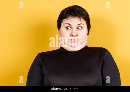 femme grosse avec double menton et regard fou sur fond jaune Banque D'Images