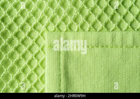 Poche cousue sur le tissu jersey de coton vert en maille macro. Texture en maille vert clair avec mesh pour des vêtements de sport modernes. Vêtements d'extérieur décontractés. Banque D'Images
