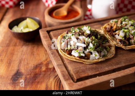 Tacos de Suadero. Viande frite dans une tortilla au maïs. Cuisine de rue de CDMX, au Mexique, traditionnellement accompagnée de coriandre, d'oignon et de sauce rouge épicée Banque D'Images