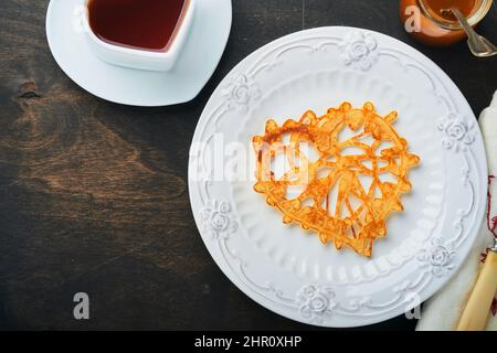 Crêpes ou crêpes en dentelle en forme de coeur sur plaque blanche sur fond rustique ancien.Table pour votre petit déjeuner préféré de la Saint-Valentin.Copie de la vue de dessus Banque D'Images