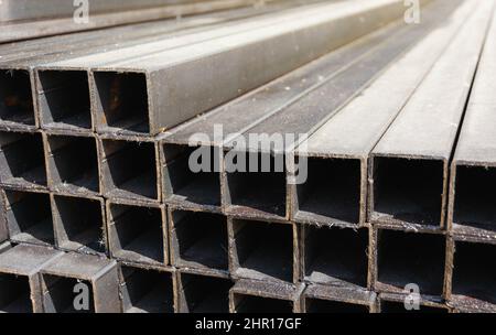 profil carré métallique dans une pile, tuyaux métalliques de section carrée sur le site d'un magasin de matériaux de construction, matériaux de construction métalliques. Banque D'Images