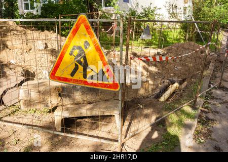 La cour est fermée avec des panneaux et une bordure autour de la rue travaille. Panneau « Construction and Road Works » dans le centre-ville. Attention, attention ! Banque D'Images