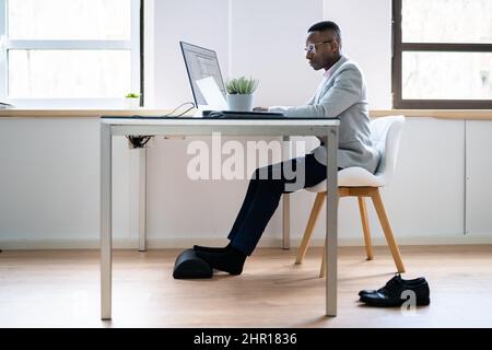 Travailleur utilisant un repose-pied pour réduire la tension du dos et la fatigue des pieds Banque D'Images