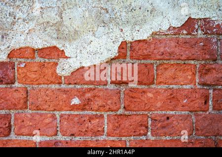 Le fond d'un mur de brique avec des restes de plâtre, la texture vide d'un vieux mur de brique. Un fragment d'une surface battue de plâtre rugueux. GR Banque D'Images