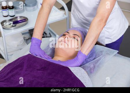 Cosmétologue se préparant à faire des traitements cosmétiques du visage pour la jeune femme. Banque D'Images