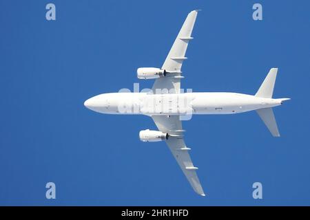 Un avion blanc en vol sur fond bleu ciel, vue de dessous Banque D'Images