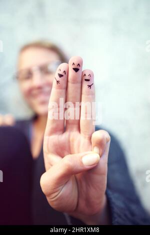 Heureux. Photo rognée des doigts avec des smileys dessinés dessus. Banque D'Images
