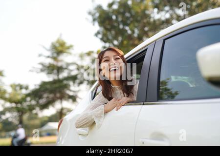 Une jeune touriste qui se trouve dans un taxi à l'arrière du siège, et qui s'est penchée hors des fenêtres, regarde la ville. Banque D'Images