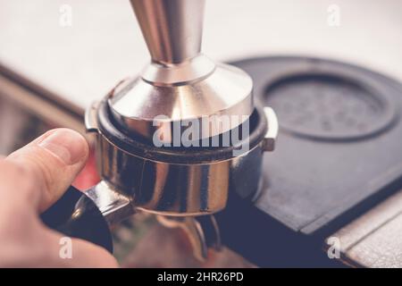 Le barista falsification du café dans le porte-filtre à l'aide d'un sabotage. Gros plan sur le processus de préparation du café frais Banque D'Images