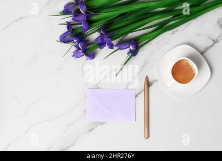 Tasse de café chaud du matin et iris violet sur fond de marbre. Pose à plat avec espace de copie pour le texte. Carte de voeux pour la Journée de la femme et le 8th mars. Banque D'Images